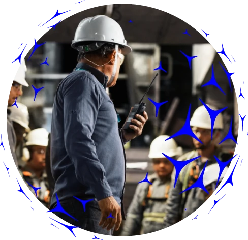 Imagem circular de uma pessoa em primeiro plano usando rádio, com trabalhadores ao fundo em ambiente industrial,  sobreposta por ícones azuis em formato de aerogeradores.