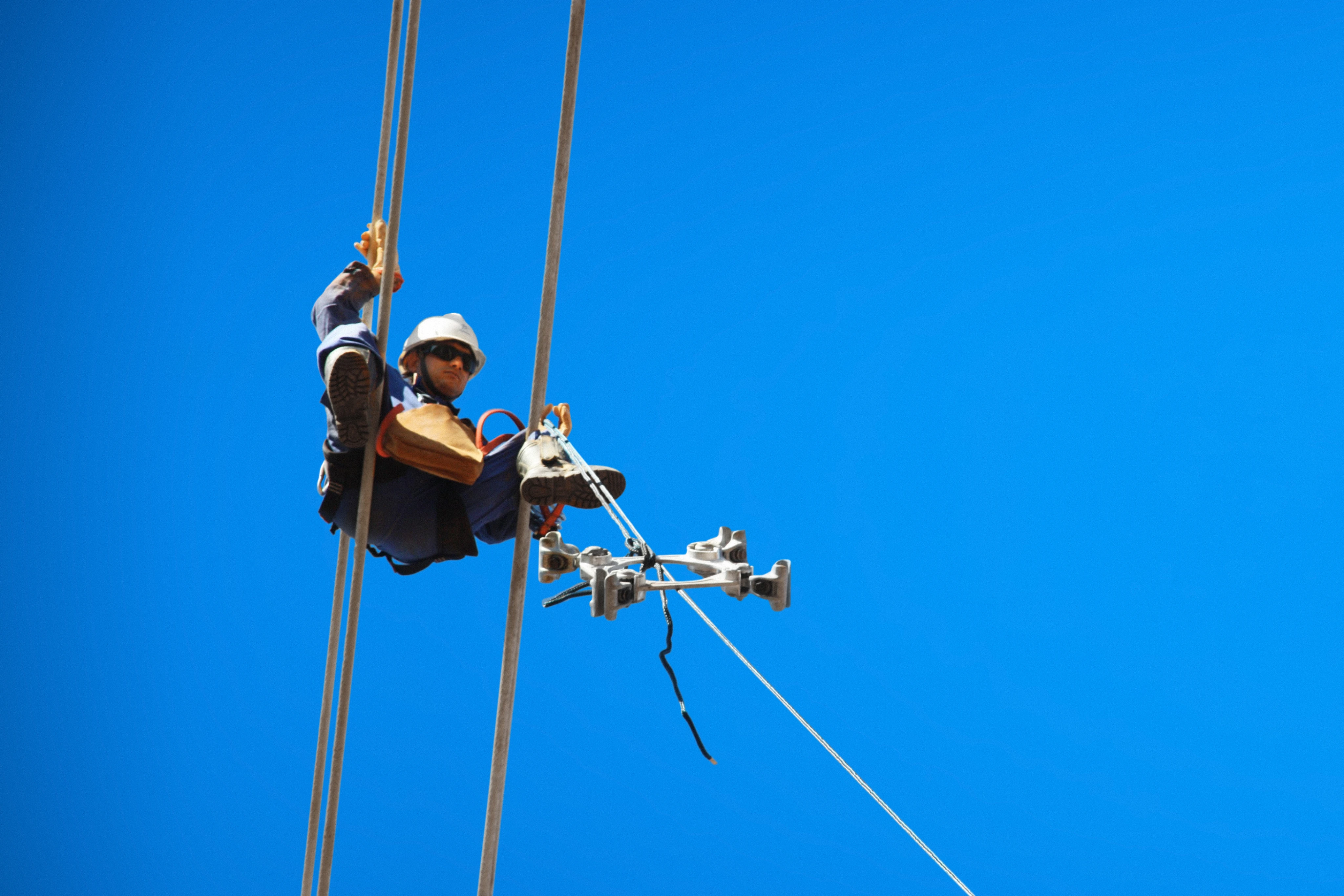 pessoa trabalhando suspensa em cabos.