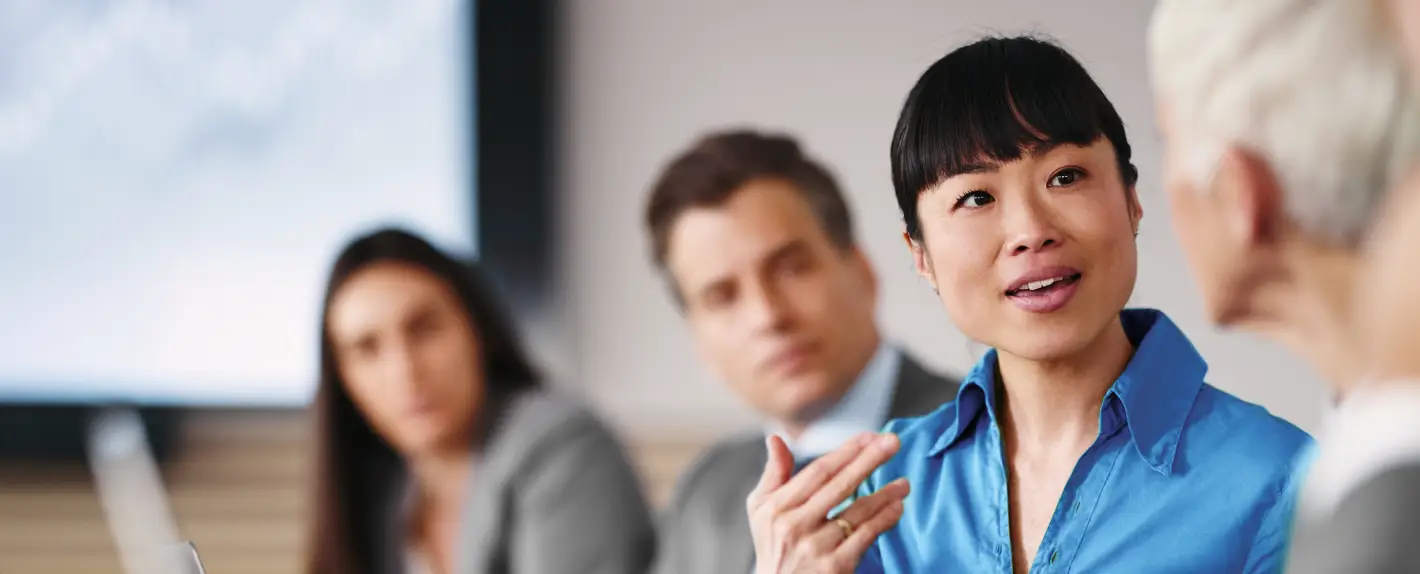 Pessoas sentadas em uma reunião, conversando e trocando ideias em um ambiente corporativo.